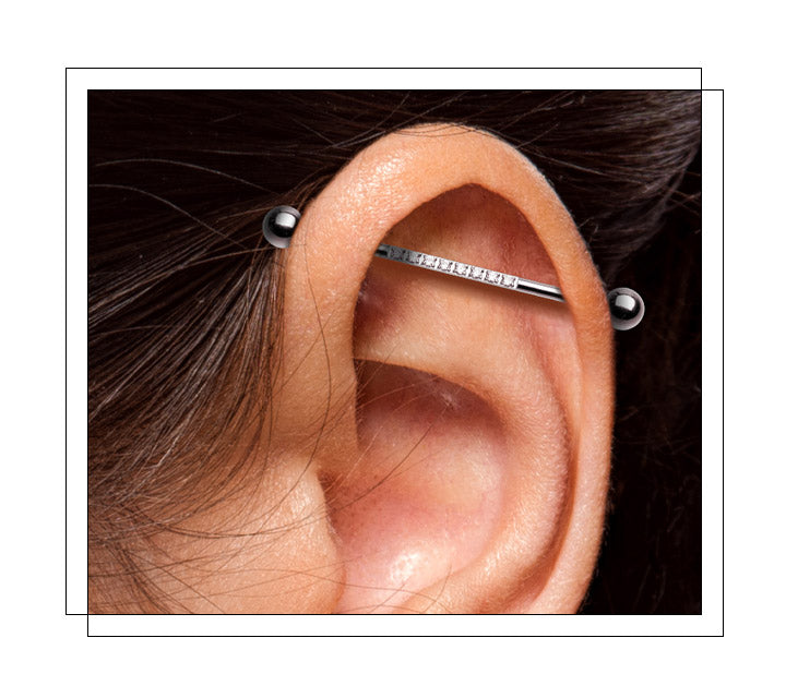 Located through the sides of the cartilage in the ear. Also, referred to as a scaffold. The barbell is first inserted from behind the ear and goes diagonally towards the front of the upper cartilage and through the second piercing, secured by a screw on directly behind the second hole. The most common idustrial piercing connects the forward helix and the antihelix.